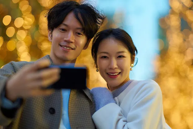 イルミネーションをバックに撮影するカップル