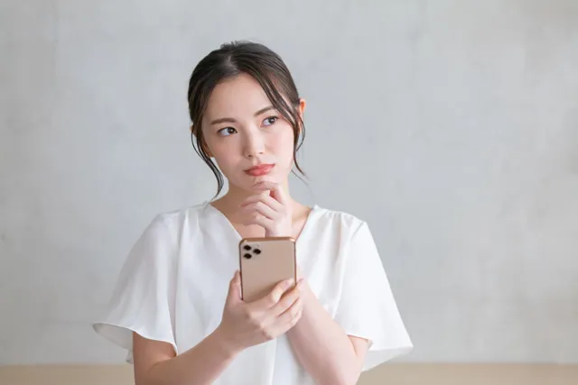 スマホを持って悩む女性