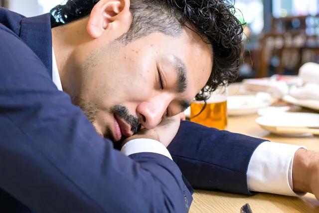 泥酔した男性が腕を枕にして寝る